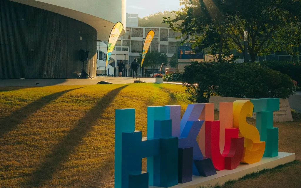 Colorful HKUST letter sign on the university lawn at sunset.