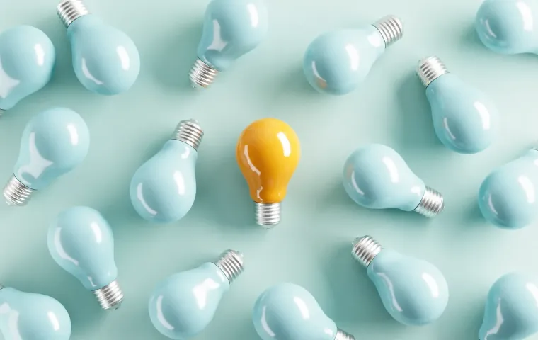 A yellow idea bulb among pale blue light bulbs.