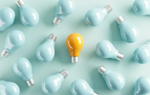 A yellow idea bulb among pale blue light bulbs.