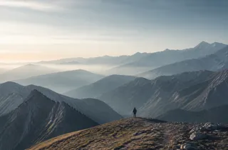 A traveller standing on a ridge and looking across a range of mountains.