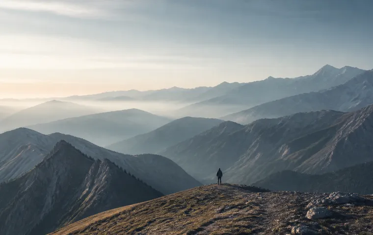 A traveller standing on a ridge and looking across a range of mountains.